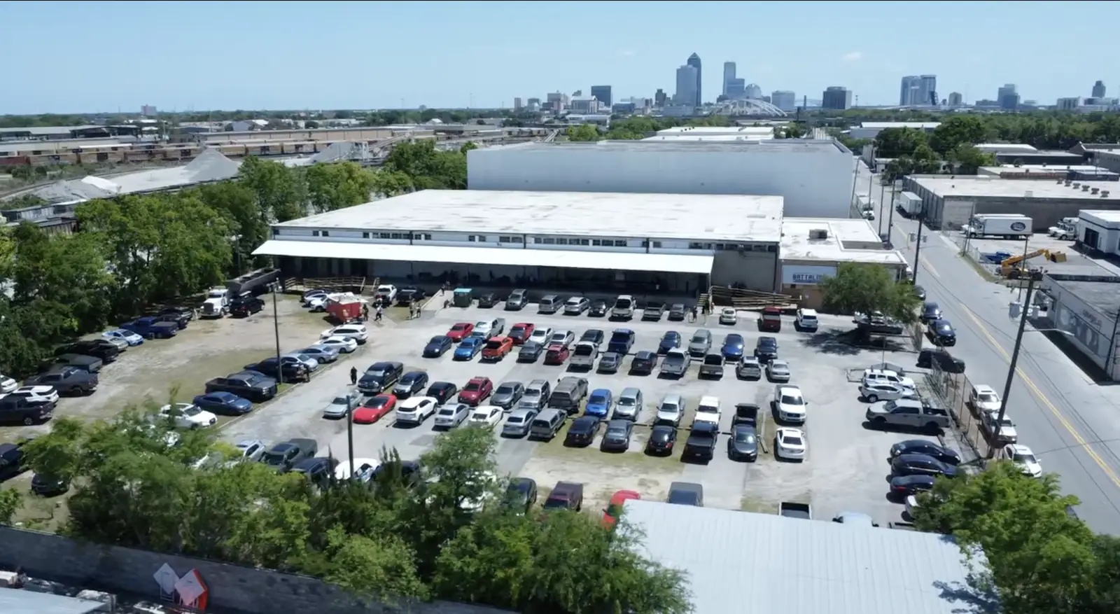 Drone view of the Battalion building and its parking lot, with the Jacksonville skyline behind